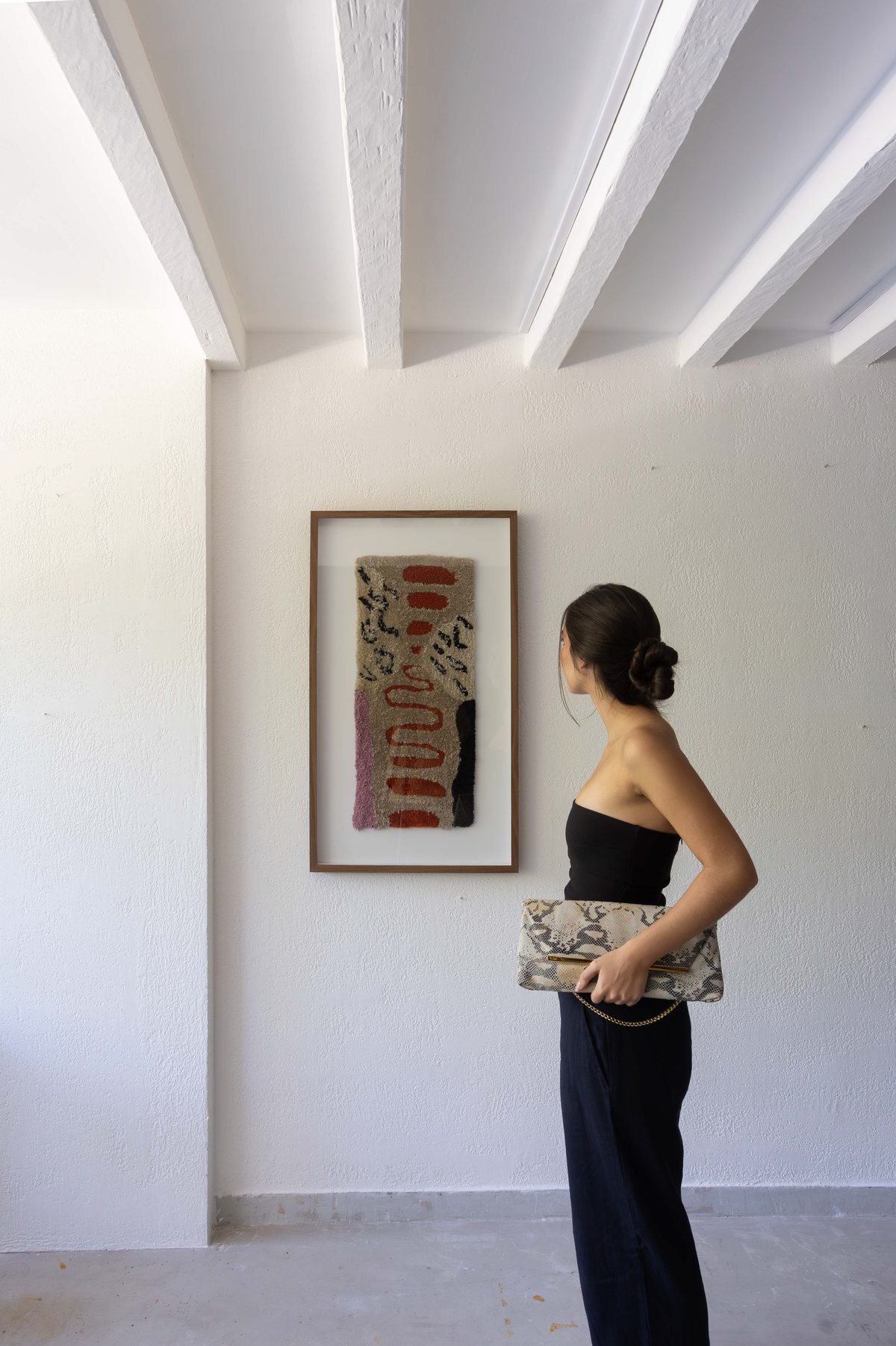 Visitante diante de uma obra têxtil emoldurada
